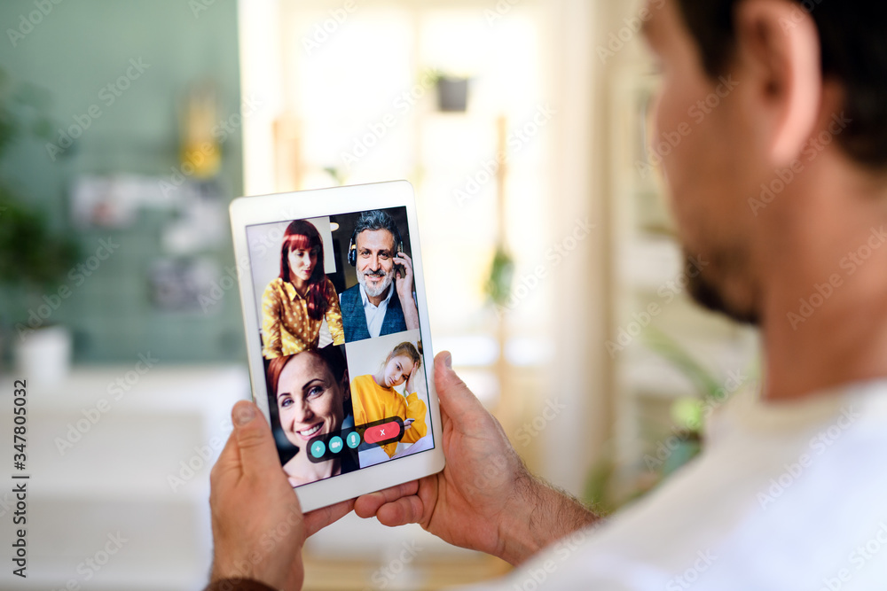 Unrecognizable man having video call on tablet at home.