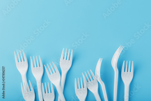 White plastic forks of disposable tableware on a blue background.