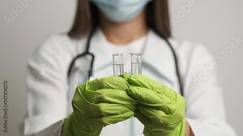 Girl doctor in a mask and gloves holds test tubes. Health, medical photo