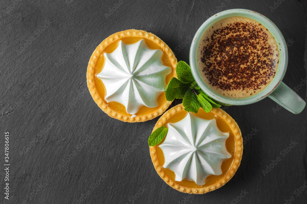 Lemon tart with mint leaves and a cup of cappuccino with chocolate topping Lemon tart with mint leaves and a cup of cappuccino with chocolate topping
