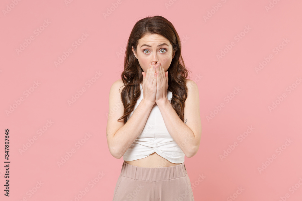 Shocked young brunette woman girl in light casual clothes posing isolated on pastel pink background studio portrait. People emotions lifestyle concept. Mock up copy space. Covering mouth with hands. Shocked young brunette woman girl in light casual clothes posing isolated on pastel pink background studio portrait. People emotions lifestyle concept. Mock up copy space. Covering mouth with hands.