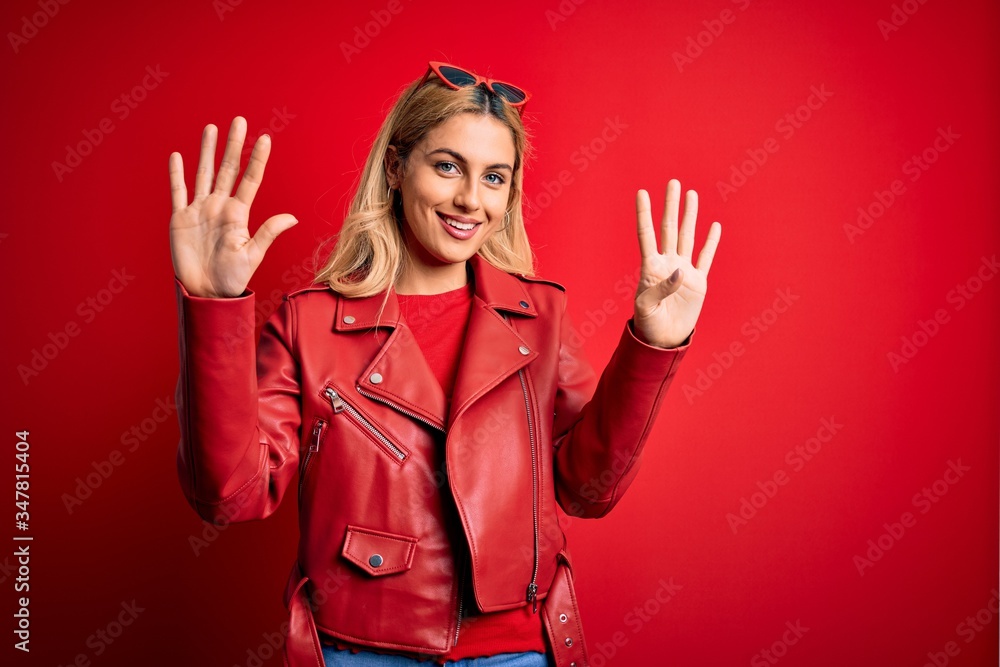Young beautiful blonde woman wearing casual jacket standing over isolated red background showing and pointing up with fingers number nine while smiling confident and happy. Young beautiful blonde woman wearing casual jacket standing over isolated red background showing and pointing up with fingers number nine while smiling confident and happy.