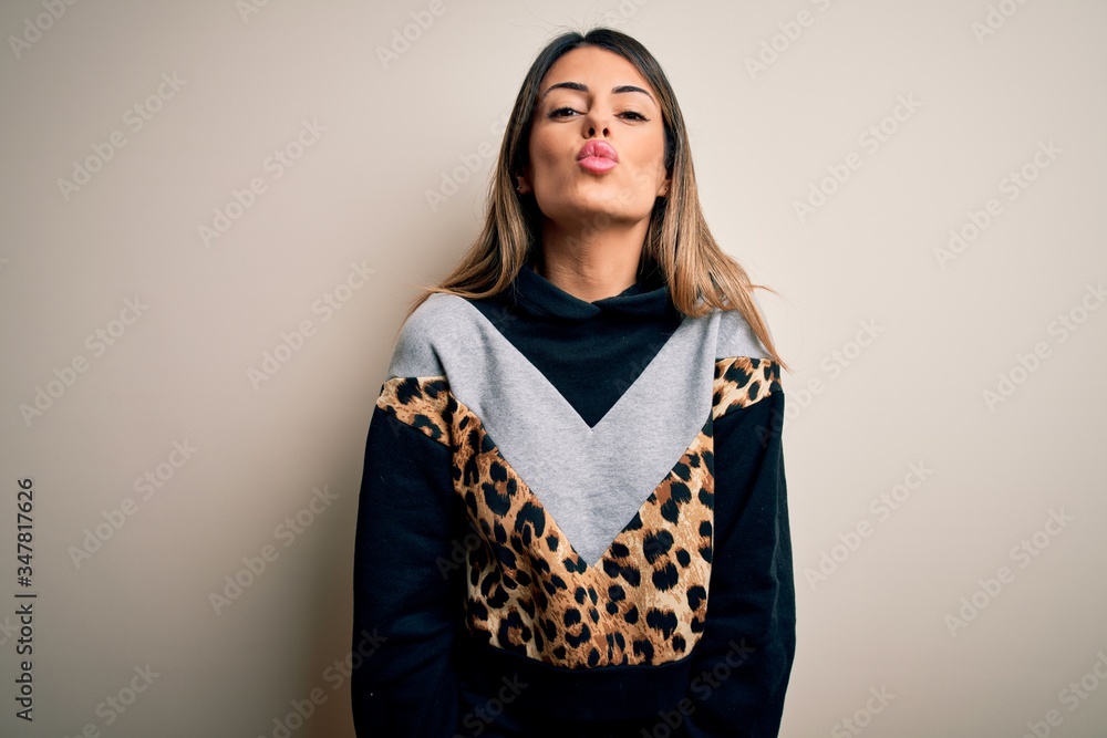 Fototapeta premium Young beautiful woman wearing casual sweatshirt standing over isolated white background looking at the camera blowing a kiss on air being lovely and sexy. Love expression.