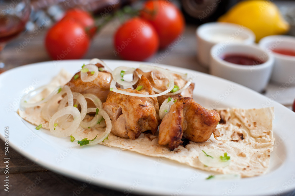 Meat kebab with onions on a white plate on a wooden background. Grilled meat Meat kebab with onions on a white plate on a wooden background. Grilled meat