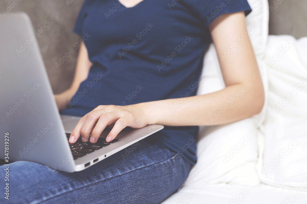 Naklejka premium laptop. lifestyle woman close up hand keyboard sit on the bedroom a using a notebook computer to work from home and search information social network online. wfh.