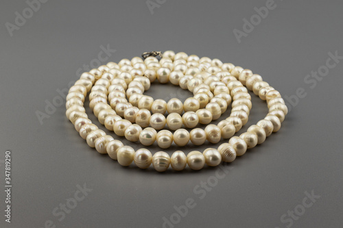 A necklace of natural pearls on a gray background.