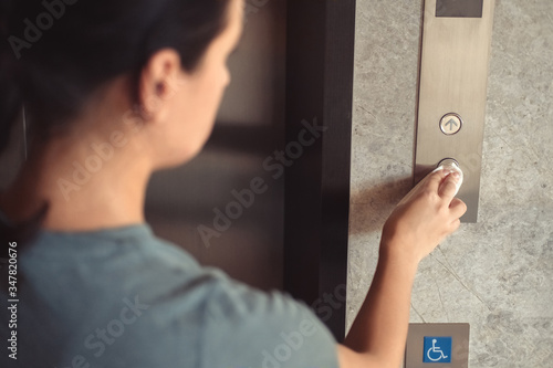 Woman pressing elevator button through tissue paper. Infection prevention and control of Corona virus Covid-19 epidemic