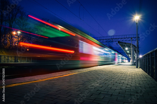 Evening arrival of the train on an empty platform. Photo taken with a shutter speed. Rays of light. Blur. Evening railway station.