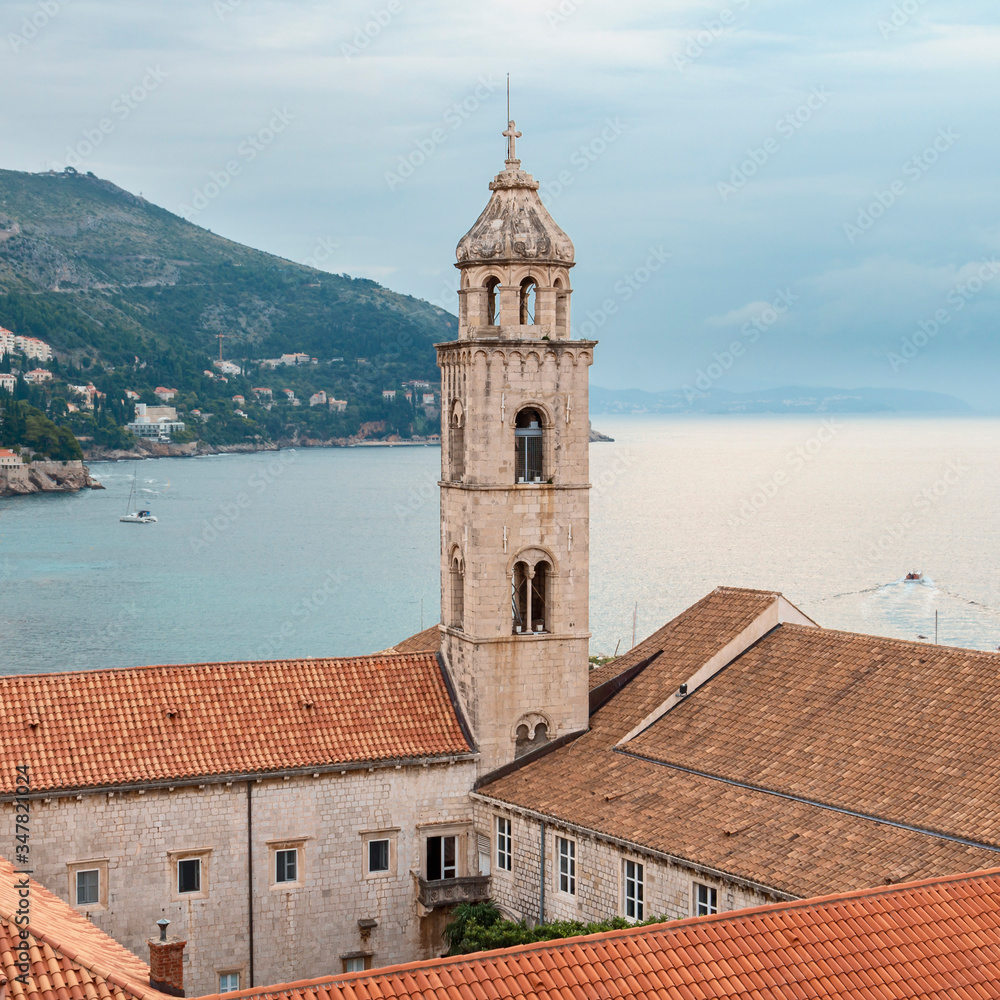 view of the watchtower and tiled roofs of the ancient Croatian city of Dubrovnik against the background of the sea and cloudy sky