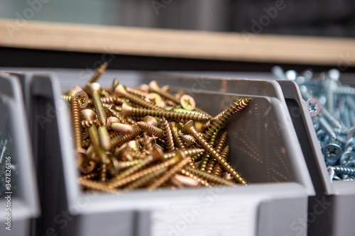 Focus on the yellow screws in the plastic boxes that are on the shelf in the tool and accessories store for the building. Copy space.