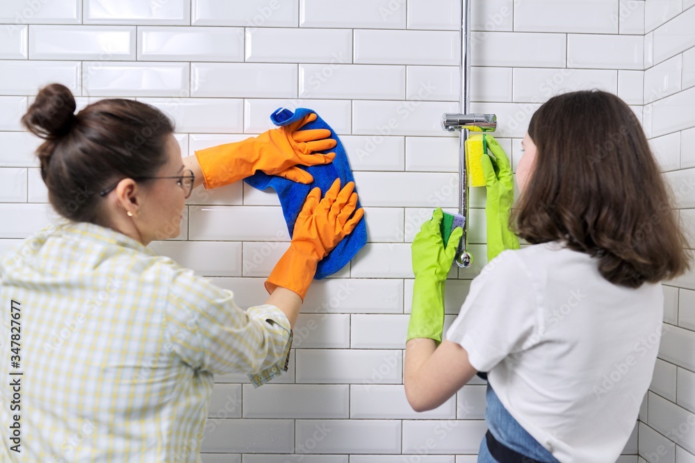 Family mother and teenage daughter cleaning together at home in bathroom Family mother and teenage daughter cleaning together at home in bathroom