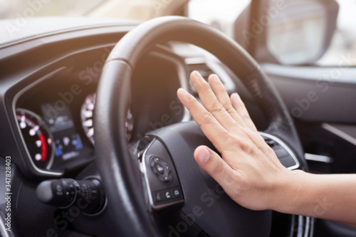 man pushing horn while driving sitting of a steering wheel press car, honking sound to warn other people in traffic concept. © methaphum