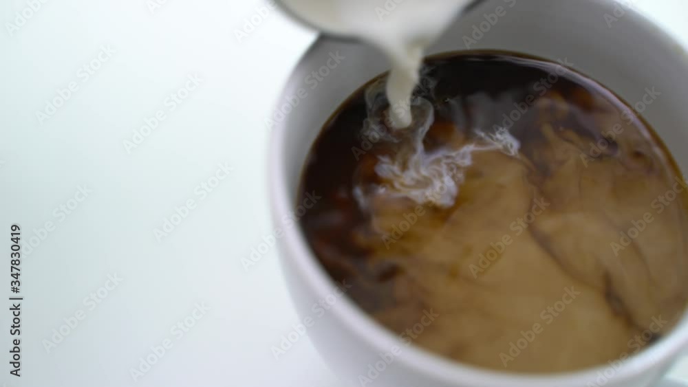 Top view and close up of person male hands put the milk into the white coffee cup and stirring coffee with spoon. 4k resolution. Top view and close up of person male hands put the milk into the white coffee cup and stirring coffee with spoon. 4k resolution.