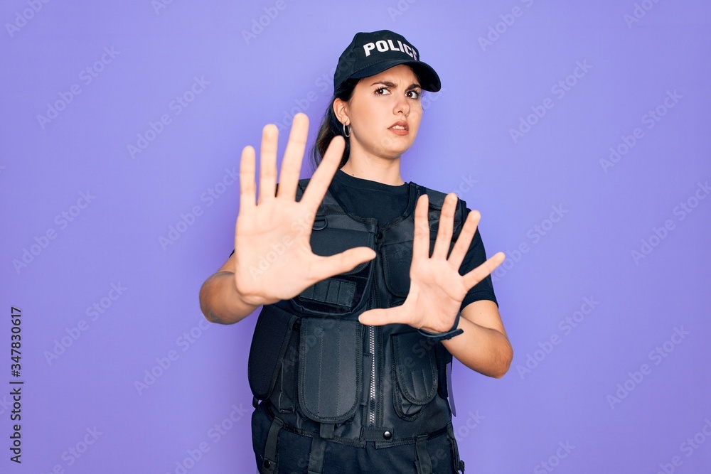 Young police woman wearing security bulletproof vest uniform over purple background Moving away hands palms showing refusal and denial with afraid and disgusting expression. Stop and forbidden. Young police woman wearing security bulletproof vest uniform over purple background Moving away hands palms showing refusal and denial with afraid and disgusting expression. Stop and forbidden.