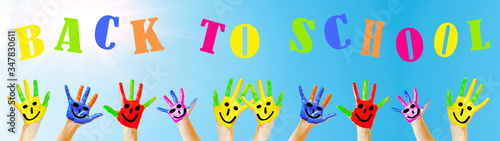 BACK TO SCHOOL banner background panorama -Many brightly painted children's hands with smileys, isolated on blue sky with sunshine and copy space