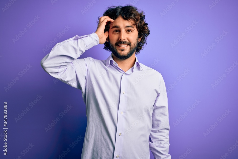 Young handsome business man with beard wearing shirt standing over purple background smiling confident touching hair with hand up gesture, posing attractive and fashionable Young handsome business man with beard wearing shirt standing over purple background smiling confident touching hair with hand up gesture, posing attractive and fashionable