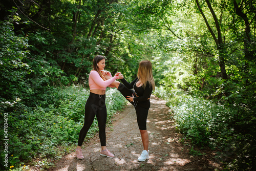 Fototapeta Naklejka Na Ścianę i Meble -  Two attractive caucasian  girls are training in the park. Health and sports