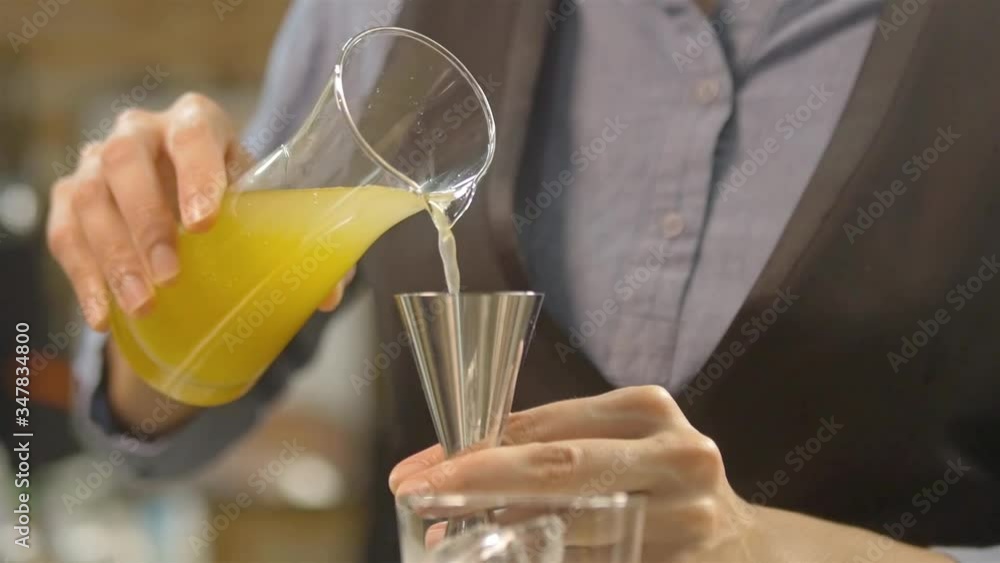 Woman pour some yellow syrup to the jigger - pan follow Woman pour some yellow syrup to the jigger - pan follow