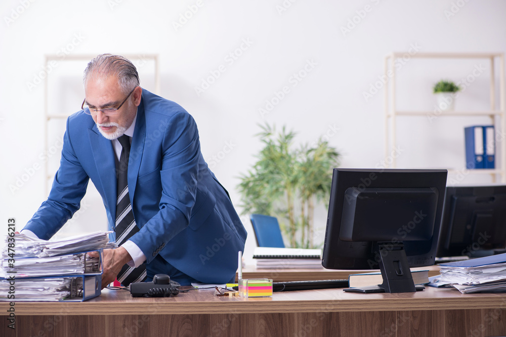 Old male employee and excessive work in the office