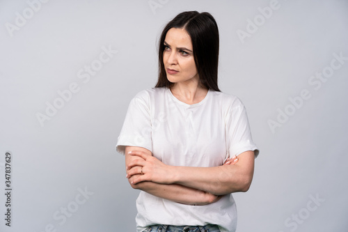 Girl in white t-shirt with long dark hair folded his hands and turned away, the concept of the emotion of resentment