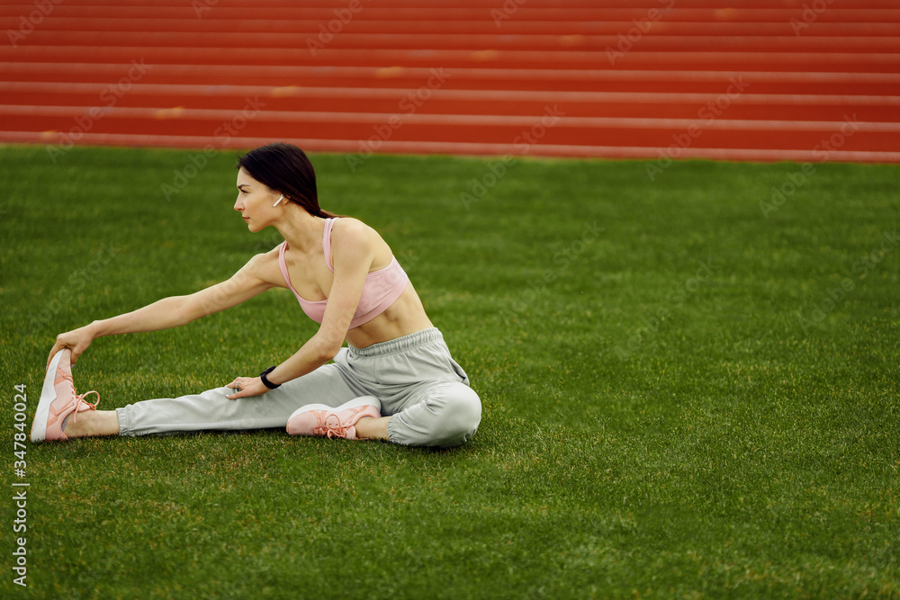 Young fitness woman doing exercises on the stadium