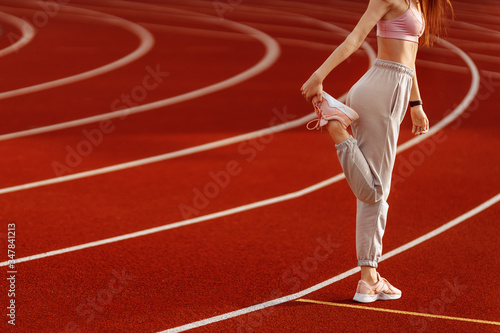 Fitness sporty woman runner stretching legs before run on the stadium
