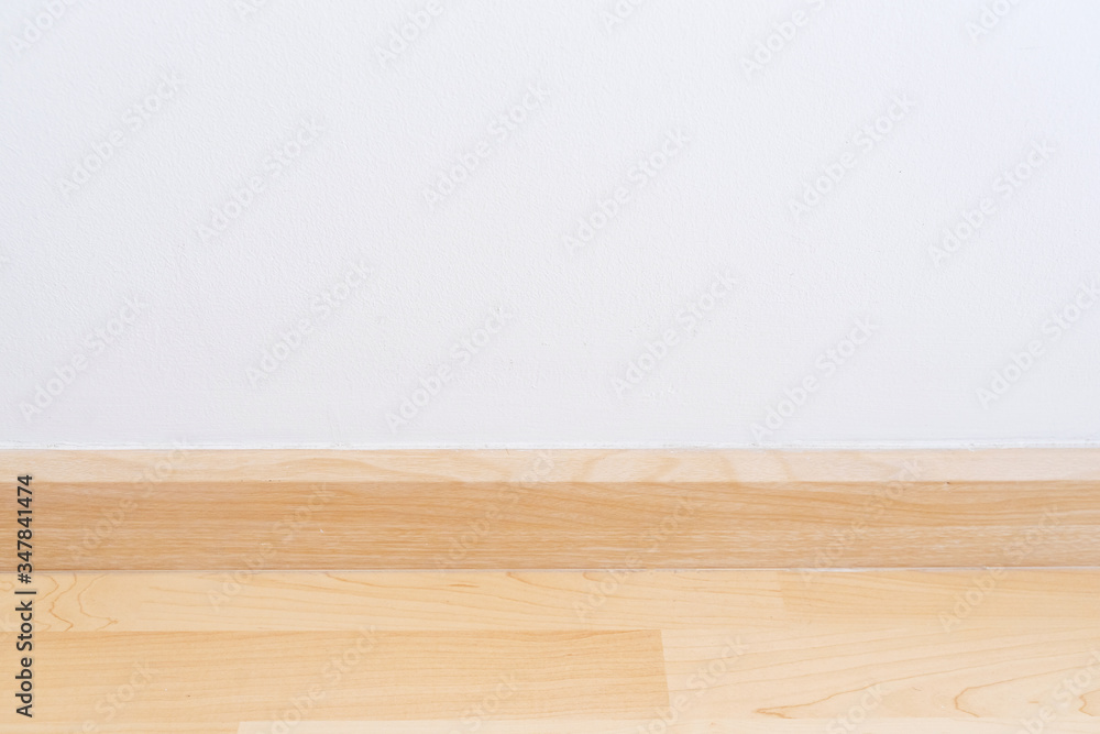 Wooden wall base skirting, finishing material with wood laminate floor and white mortar wall. Empty room with white wall and wooden floor. Wooden wall base skirting, finishing material with wood laminate floor and white mortar wall. Empty room with white wall and wooden floor.