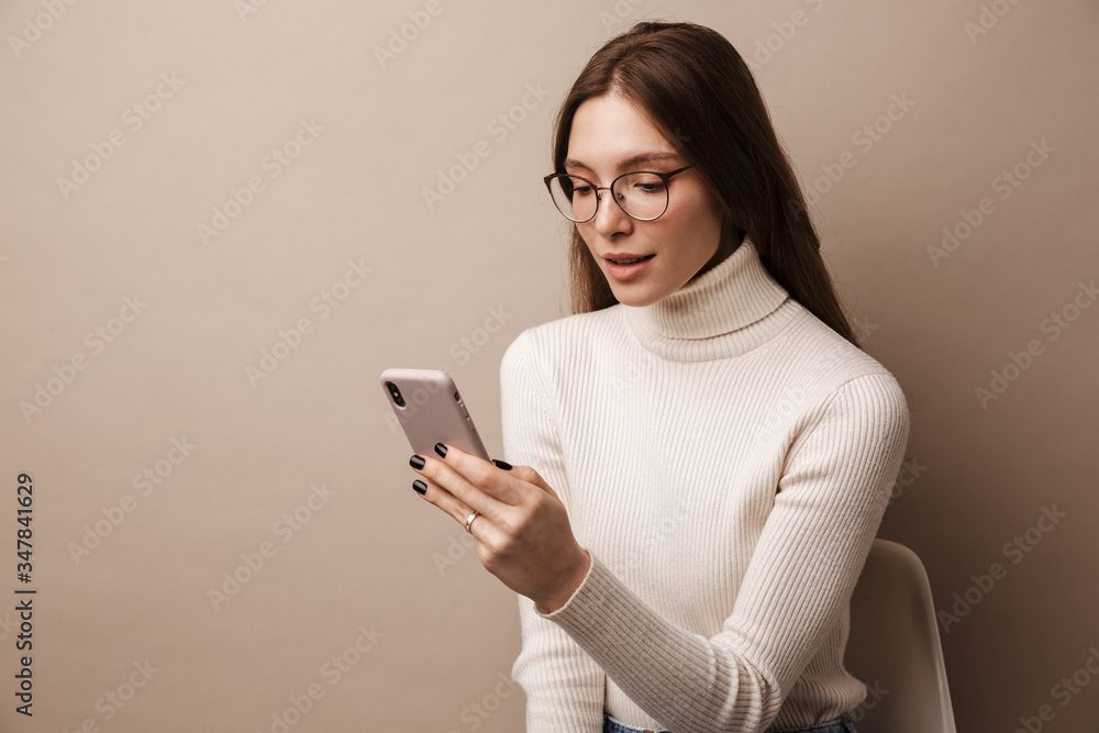 Photo of charming focused woman using cellphone and sitting on chair Photo of charming focused woman using cellphone and sitting on chair