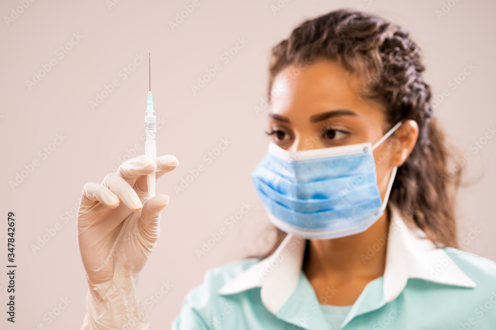 Portrait of young nurse who is holding syringe. Shallow depth of field.