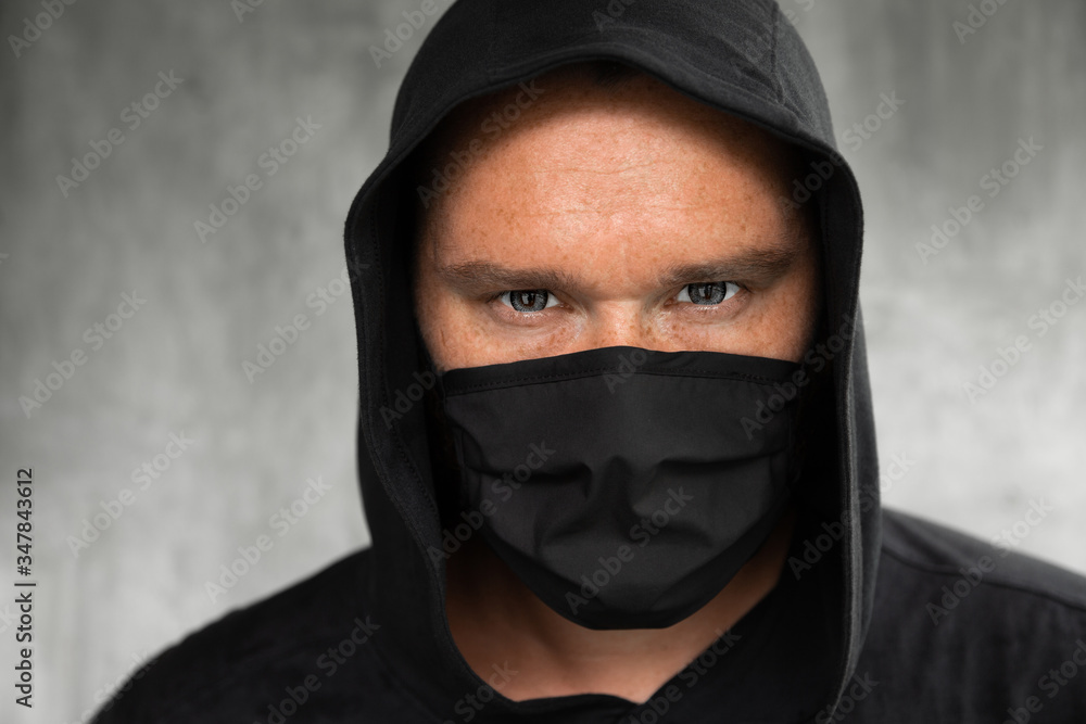 A man in a hood and a white medical mask A man in a hood and a white medical mask