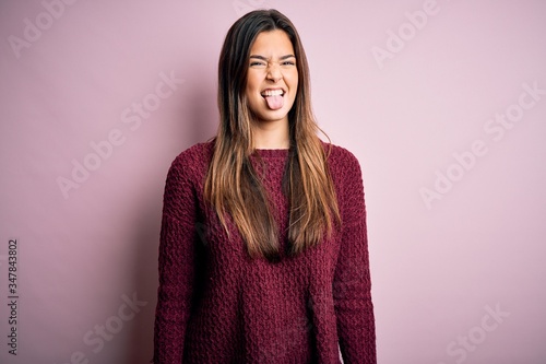 Young beautiful girl wearing casual sweater over isolated pink background sticking tongue out happy with funny expression. Emotion concept. © Krakenimages.com