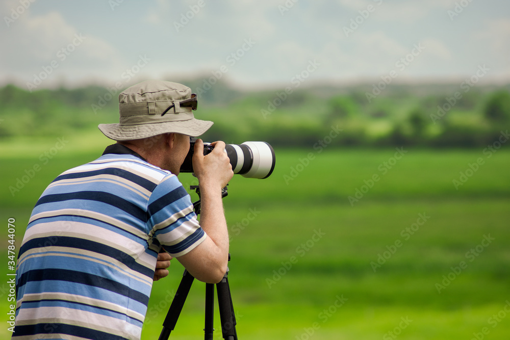 Obraz premium Man in a hat taking a picture at summer. Place for text.