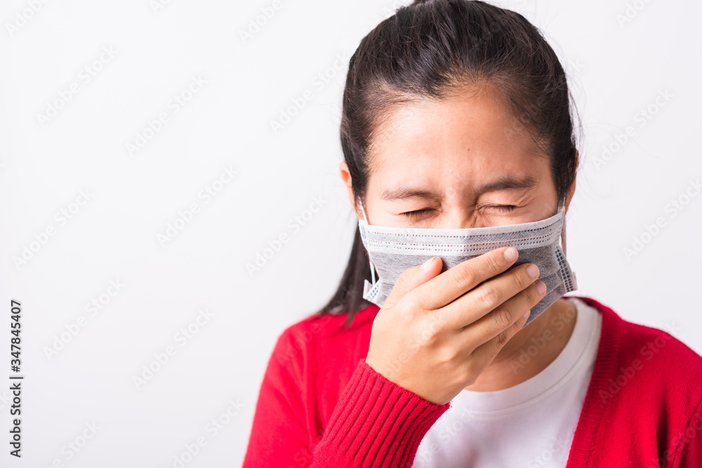 Closeup Asian adult woman wearing red shirt and face mask protective against coronavirus or COVID-19 virus or filter dust, air pollution her sneezing use hand close mouth, isolated white background Closeup Asian adult woman wearing red shirt and face mask protective against coronavirus or COVID-19 virus or filter dust, air pollution her sneezing use hand close mouth, isolated white background