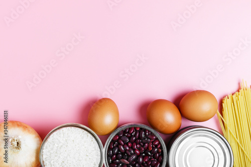  Eggs, rice, beans, pasta, canned food on a pink background. Concept of food delivery and food donation during quarantine isolation during the coronavirus pandemic. online grocery shopping. copy space