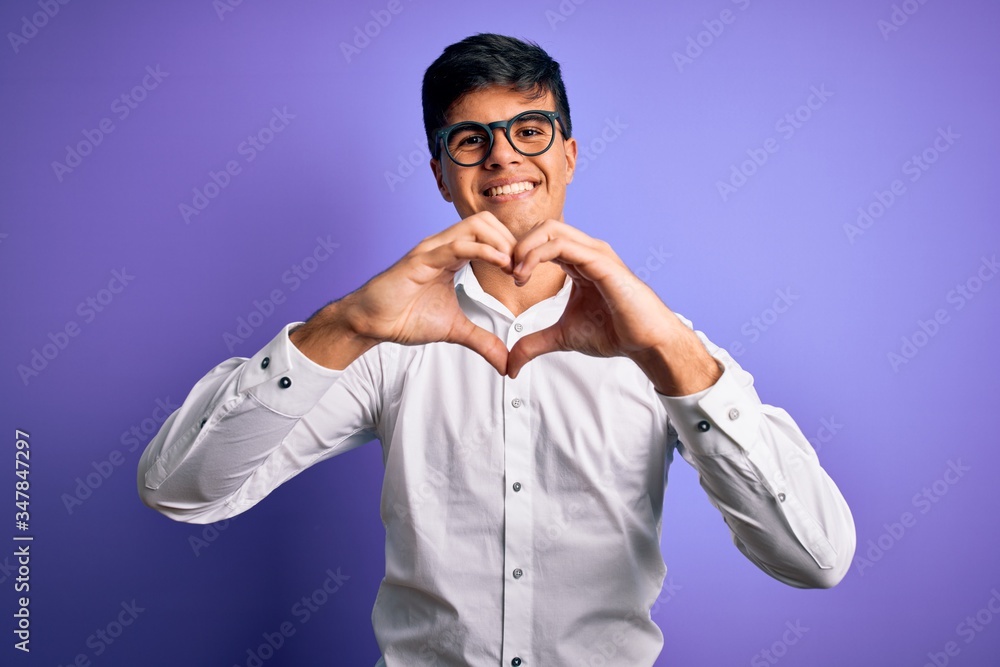 Young handsome business man wearing shirt and glasses over isolated purple background smiling in love doing heart symbol shape with hands. Romantic concept. Young handsome business man wearing shirt and glasses over isolated purple background smiling in love doing heart symbol shape with hands. Romantic concept.