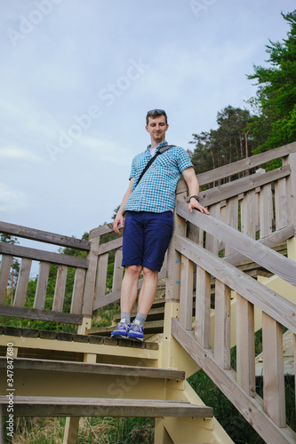 man sitting on the wooden stairs in park and smiling