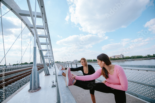 Two attractive young caucasian women are doing exercises on the bridge