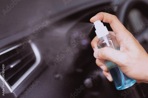 Hand of man that spraying alcohol disinfectant on Air conditioner in his car prevent infection of Covid-19  Corona virus contamination of germ bacteria wipe clean surfaces that are frequently touched.