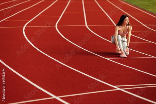 Athlete woman tying shoelaces before running at the stadium