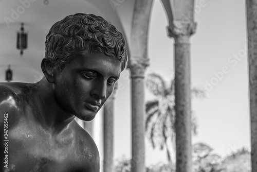 Black and white photo showing young male face of bronze statue in closeup