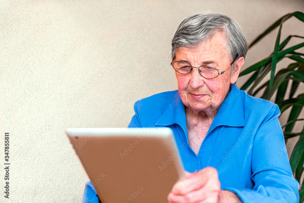 old grandmother reads the latest news from the electronic tablet. development of new technologies. old grandmother reads the latest news from the electronic tablet. development of new technologies.