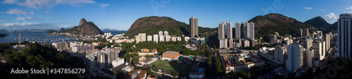 Super wide panorama of Botafogo and Urca neighbourhoods in Rio de Janeiro with high rise buildings and mountains such as the Sugarloaf mountain against a clear blue sky © Maarten Zeehandelaar