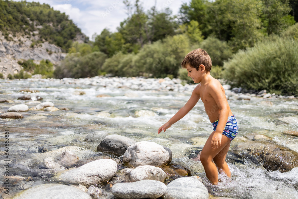 Fototapeta premium Little child in the middle of a wild river