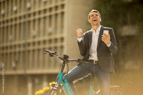 Young businessman on the ebike received gret news by mobile phone photo