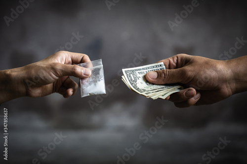 Hand of addict man with money buying dose of cocaine or heroine, close up of addict buying dose from drug dealer, drug trafficking, crime, addiction and sale concept, photo