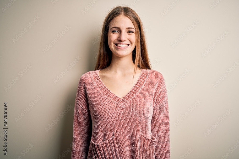 Young beautiful redhead woman wearing pink casual sweater over isolated white background with a happy and cool smile on face. Lucky person. Young beautiful redhead woman wearing pink casual sweater over isolated white background with a happy and cool smile on face. Lucky person.