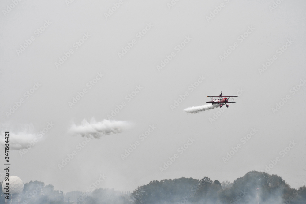 Red antique airplane flying during a grey day Red antique airplane flying during a grey day