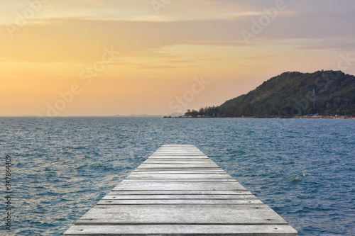 Fototapeta Naklejka Na Ścianę i Meble -  Sunset at sea and old wooden bridgeมPerspective view of wooden pier on the sea at sunset with perfectly specular reflection,wooden retro deck and sunrise or sunset sky/ Summer holidays background.