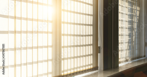 large window with windowsill and beige textile shutters with hard sunlight
