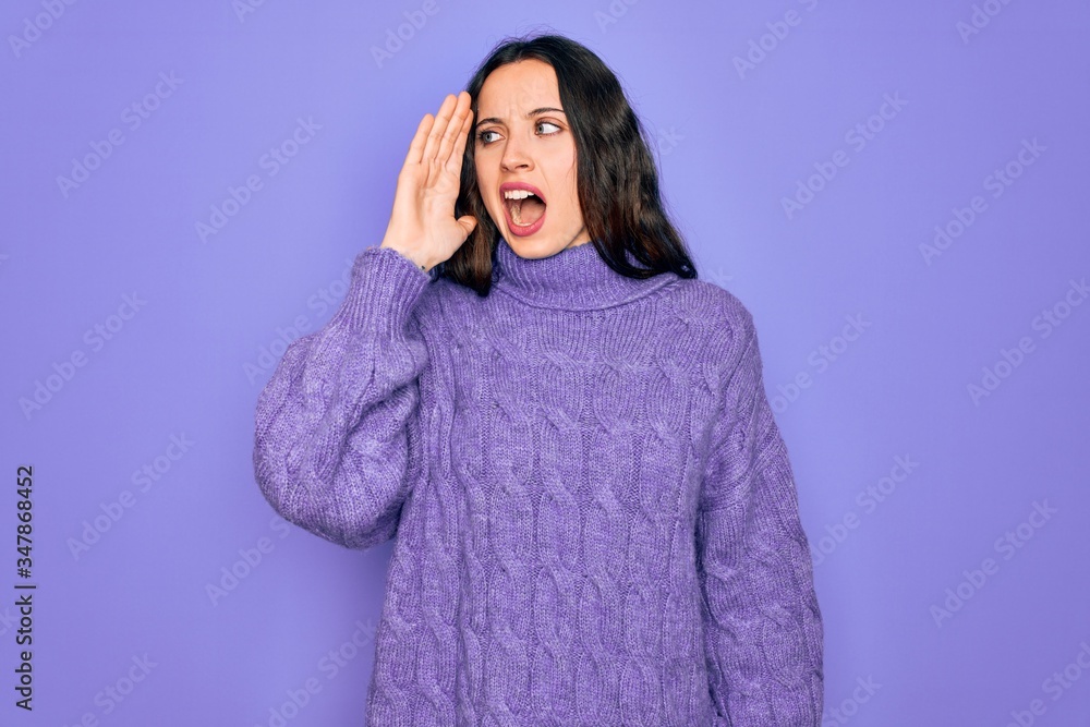 Young beautiful woman wearing casual turtleneck sweater standing over purple background shouting and screaming loud to side with hand on mouth. Communication concept. Young beautiful woman wearing casual turtleneck sweater standing over purple background shouting and screaming loud to side with hand on mouth. Communication concept.
